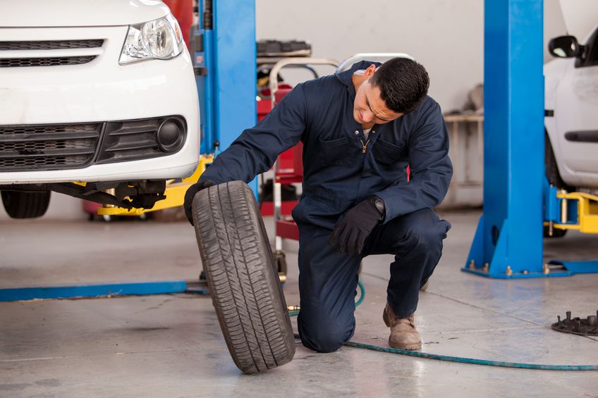 20408421 - young mechanic inspecting a car tire at an auto shop